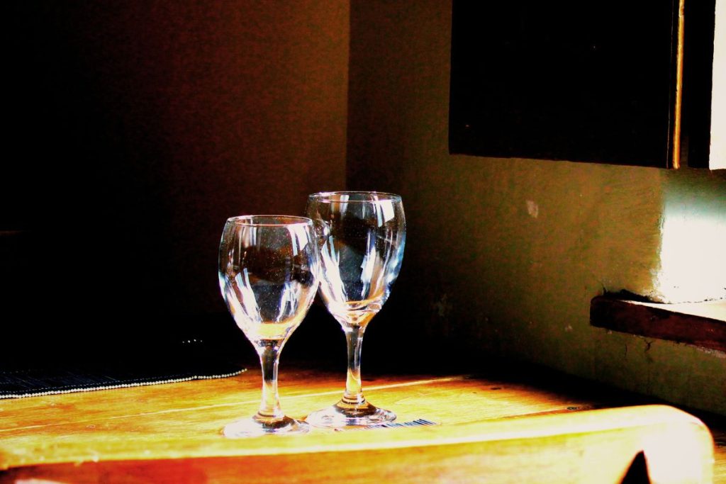 two wine glasses on a wooden table by a window in soft natural light