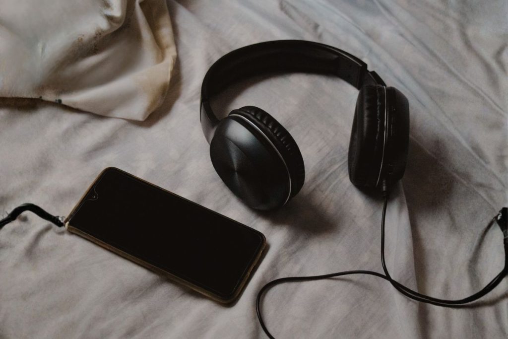 black headphones and phone resting on soft fabric, minimal and calm listening setup