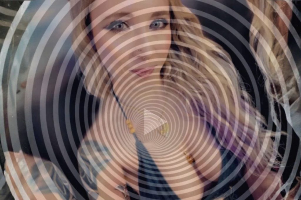 Blonde woman with blue eyes under spiral overlay looking directly at viewer