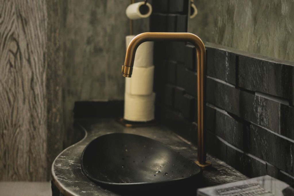 Private, moody sink and faucet in a masculine, minimal space